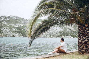 deniz kenarında güzel görünümü ile oturan adam. arka planda dağlar. Yaz saati
