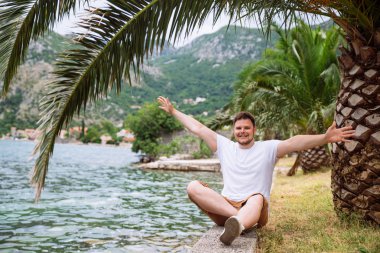 deniz kenarında güzel görünümü ile oturan adam. arka planda dağlar. Yaz saati