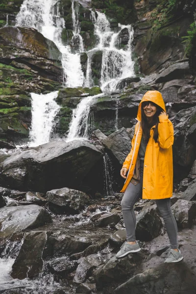 Жінка Стоїть Жовтому Плащі Дивиться Водоспад Концепція Пішохідного Туризму — стокове фото