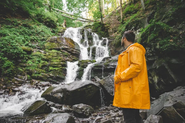 Man Permanent Gele Regenjas Kijken Naar Waterval Wandelen Concept — Stockfoto