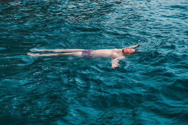 man swimming on back in blue transparent sea water. summer vacation