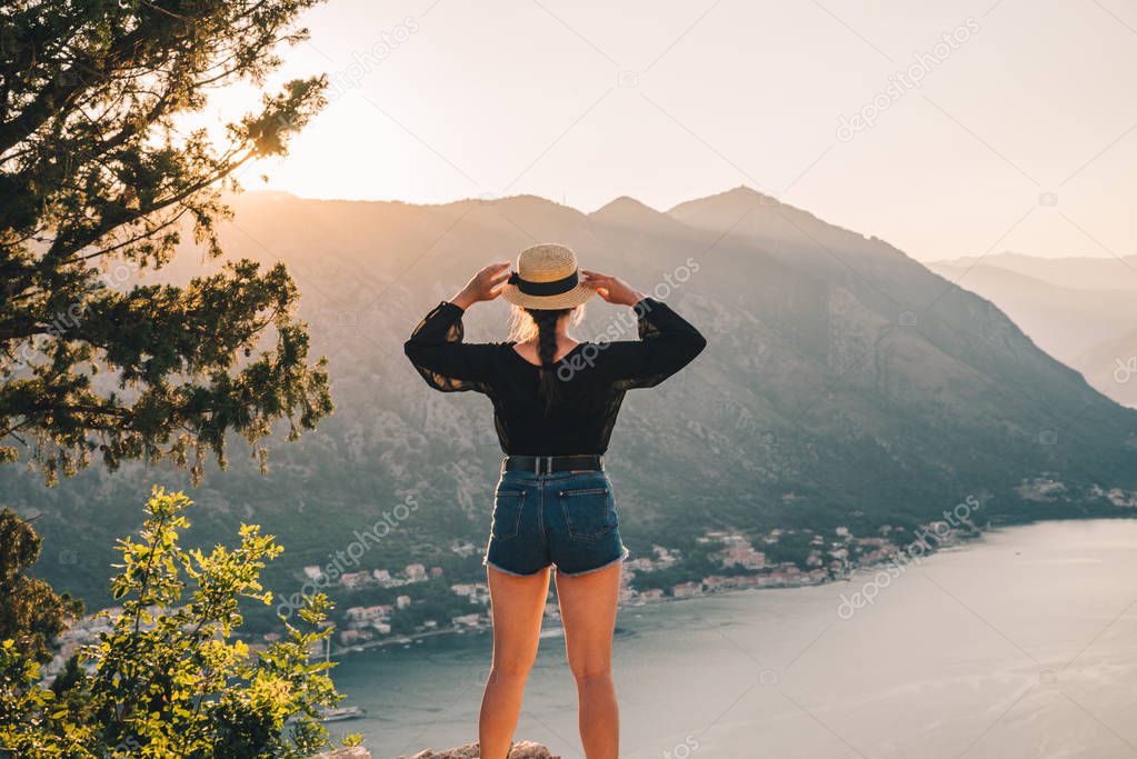 woman standing on the top of hill. kotor with sunset on background. summer travel concept