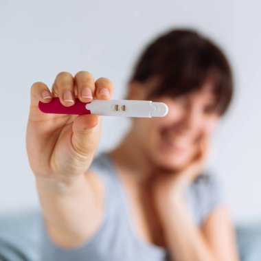 pozitif gebelik testi üzerinde seyir yatakta oturan genç mutlu kadın