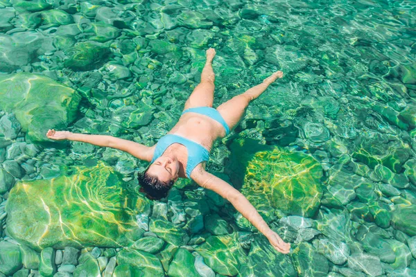 woman swimming on back in clear blue sea water. summer vacation concept