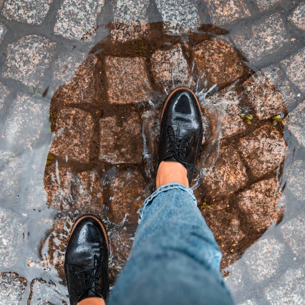 Première personne point de vue femme étape dans la flaque d'eau dans des chaussures noires — Photo