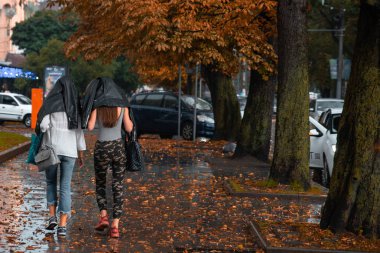 yağmur kat altında gizli iki genç yetişkin kadın. Sonbahar geliyor