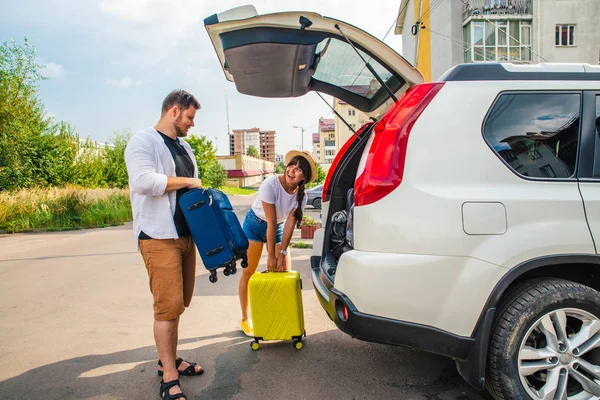 car travel concept. opened trunk with luggage inside woman with man near it. road trip