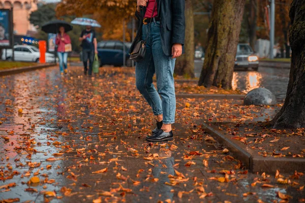 雨の後のウェット通りで歩いている女性 地面に黄色の葉 秋が来ています — ストック写真