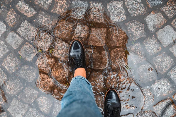 first person point of view woman step into puddle in black shoes. autumn is coming