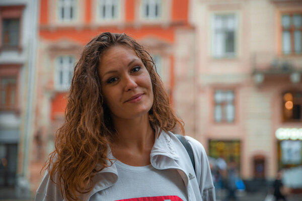 LVIV, UKRAINE - September 7, 2018: young pretty woman walking by center of european town after rain