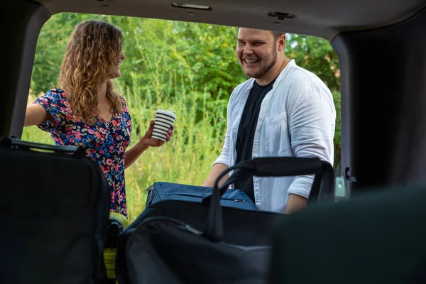 couple put bags in car trunk. road trip concept