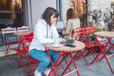 kafede farklı masada oturan iki kadın. latte içmek. dizüstü bilgisayar üzerinde çalışıyor. yaşam tarzı kavramı