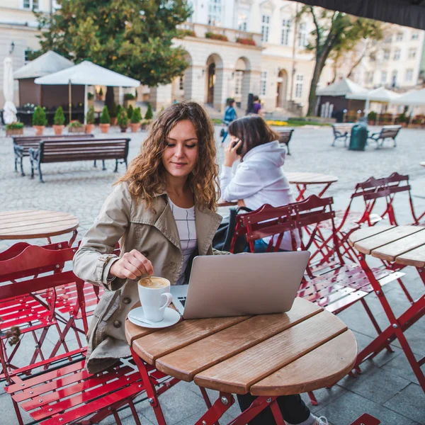 两个女人在咖啡馆里坐在不同的餐桌上 喝拿铁在笔记本电脑上工作 生活方式概念 — 图库照片
