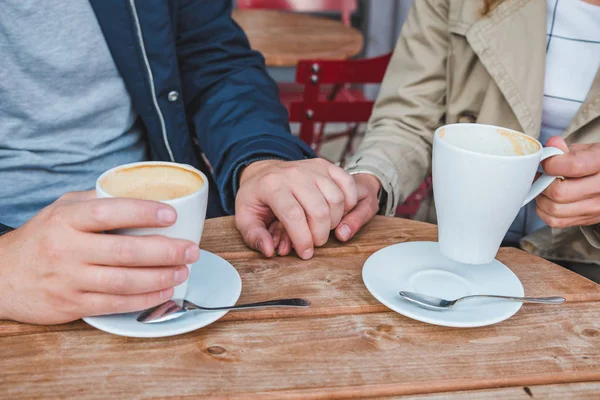 情侣在户外咖啡馆喝拿铁咖啡时手牵着手 — 图库照片