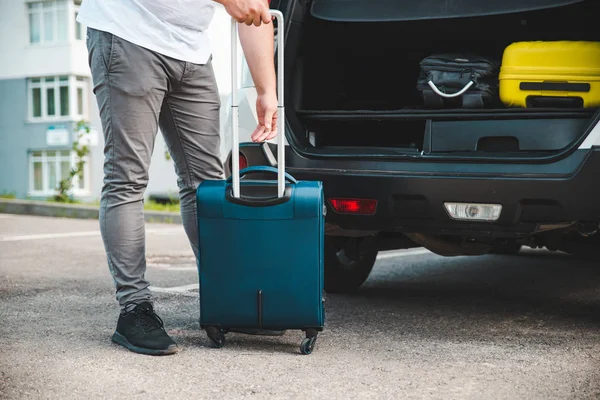 man load bags in car trunk. preparation for road trip. car travel concept