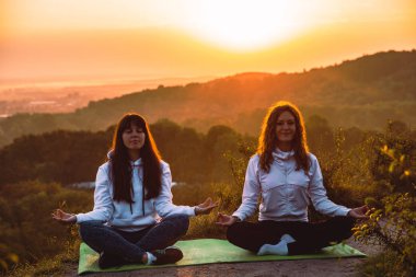 tepenin kenarında oturan kadınlar birkaç. sunrise Yoga egzersizleri yapın. sağlıklı yaşam tarzı