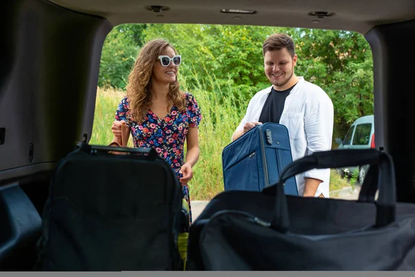 couple put bags in car trunk. road trip concept