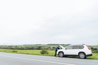 adam ayakta kırık araba ile açılan kukuleta yakınındaki. Acil servis. başarısız bir yolculuk