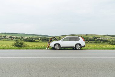 kadın ayakta kırık araba açılan kukuleta ile yol kenarında. yolda kaza