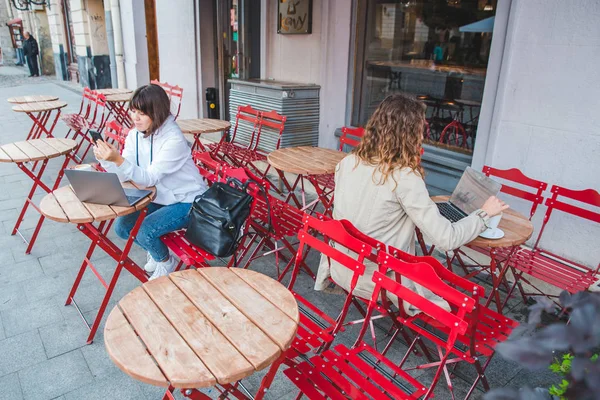 Две Женщины Кафе Сидящие Другим Столом Пить Латте Работает Ноутбуке — стоковое фото