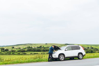 adam ayakta kırık araba ile açılan kukuleta yakınındaki. Acil servis. başarısız bir yolculuk
