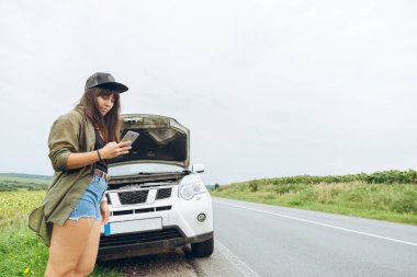 karayolu üzerinde kırık araba yakın duran ve Evet Genç Yetişkin kadın. Arama araba servisi