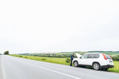 adam ayakta kırık araba ile açılan kukuleta yakınındaki. Acil servis. başarısız bir yolculuk