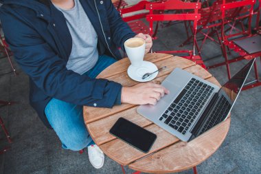 yükü görüntülemek şehir kafede dizüstü bilgisayarda çalışırken kahve tutan kadın