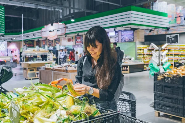 woman choosing corn in grocery shop. copy space