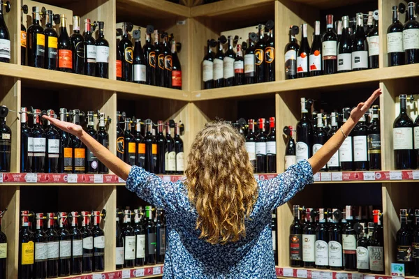 リヴィウ ウクライナ 2018 女性の食料品店でワインの棚のボトルを見て — ストック写真