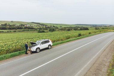 ıssız bir yerde yol kenarında, kırık araba hava görünümünü. adam ayakta ve motor arıyorum