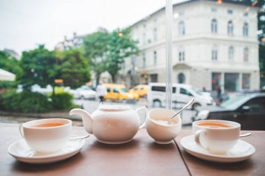 İki bardak çay ve beyaz su ısıtıcısı büyük cam pencere ile kafe tablosundaki ile. Sonbahar sezon