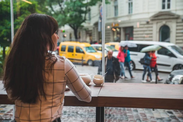 Kvinde Sidder Cafe Med Stort Glasvindue Smuk Udsigt Byens Gade - Stock-foto