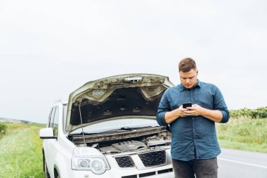 adam telefonu ile kırık araba önünde dur. hiçbir yerin ortasında kırık