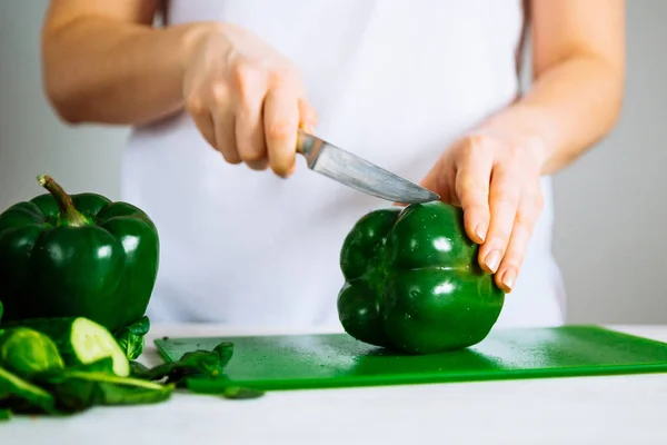 woman cut green paper on green kitchen board
