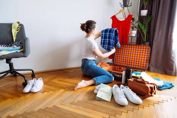 woman sit on floor. packing clothes for trip. travel concept. copy space