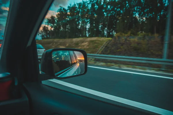 Coche en la carretera. puesta de sol en el espejo del coche reflexión —  Fotos de Stock