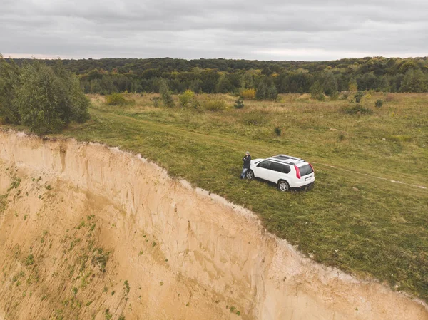 Suv blanc au sommet de la colline par temps couvert d'automne. homme debout près de la voiture autour de la nature sauvage — Photo