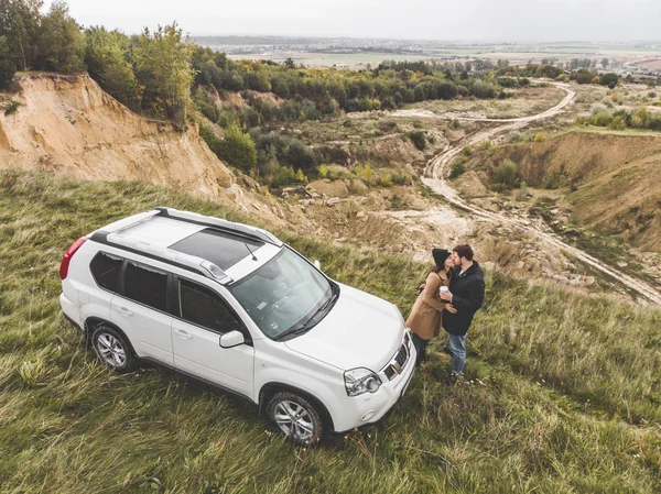 Coppia in piedi vicino suv auto presso la scogliera con bella vista dall'alto . — Foto Stock