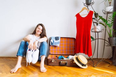 valiz giysileri ile yakın katta gülümseyen kadın sit. yolculuk öncesi ambalaj. seyahat kavramı. kopya alanı