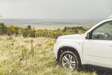 Sonbahar yağmurlu havalarda tepenin üstündeki SUV araba. kopya alanı