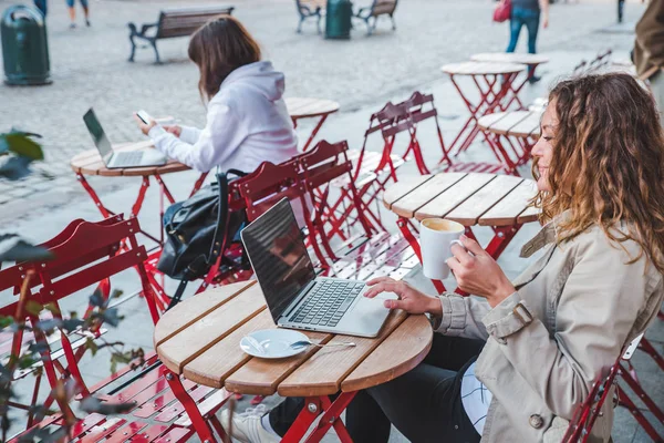两个女人在咖啡馆里坐在不同的餐桌上 喝拿铁在笔记本电脑上工作 生活方式概念 — 图库照片