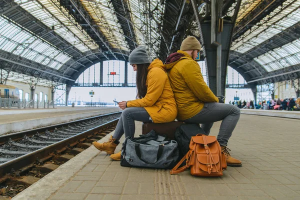 Verveeld Paar Zitten Hun Zakken Wachten Voor Trein Bekijk Telefoons — Stockfoto