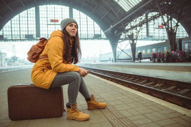 Tren Tren İstasyonu için kadın bekleyin. seyahat kavramı. zaman öldürmek için telefona internet sörf