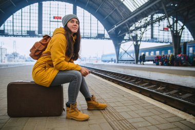 Tren Tren İstasyonu için kadın bekleyin. seyahat kavramı. zaman öldürmek için telefona internet sörf