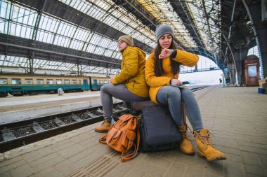İki valiz tren istasyonunda oturmak. kadın onay zaman treni beklerken. seyahat kavramı