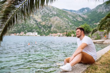 deniz kenarında güzel görünümü ile oturan adam. arka planda dağlar. Yaz saati