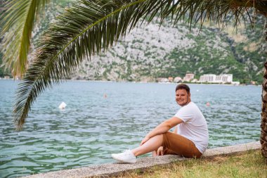 deniz kenarında güzel görünümü ile oturan adam. arka planda dağlar. Yaz saati