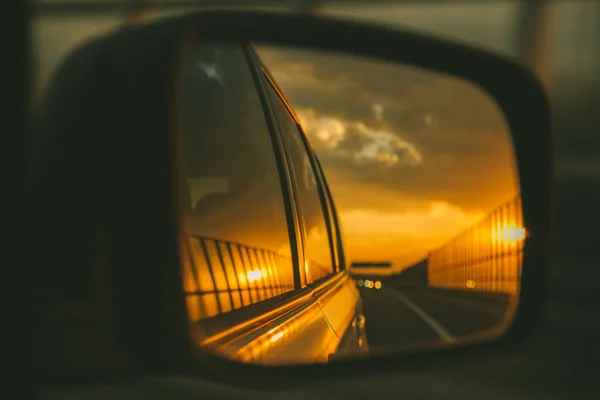 car on highway. sunset in car mirror reflection. road trip