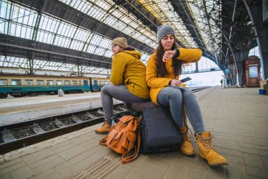 İki valiz tren istasyonunda oturmak. kadın onay zaman treni beklerken. seyahat kavramı